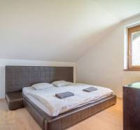 Bedroom in a Holiday Apartment with a double bed, window, wooden furniture, and sloping ceilings.
