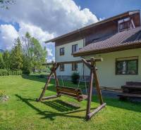 A garden with a wooden swing and a bench at the Recreational Apartment in the High Tatras.