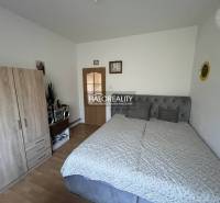 Bedroom in a 3-room apartment with a bed, wardrobe, and radio on a wooden floor.