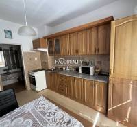 A kitchen in a 3-room apartment with wooden cabinets and equipment, a table with a tablecloth.