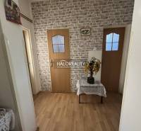 A hallway in a 3-room apartment with a brick pattern on the wall and wooden doors.
