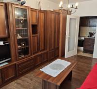 Living room with a wooden wall unit, chandelier, and table in a two-room apartment.