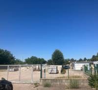 Commercial land on Popradská Street in Bratislava - Podunajské Biskupice with a gate and containers.