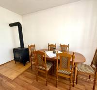 In the interior of the family house, you can see a stove and a dining table with wooden chairs.