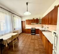 A kitchen in a family house with a stove, a dining table, and storage cabinets.