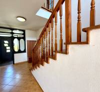 The interior of a family house with a wooden staircase and entrance doors.