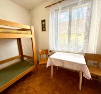 A room in a family house with a bunk bed, a table, and chairs.
