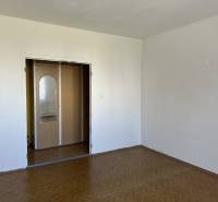Empty room with white walls and a door with a mirror in a studio apartment.