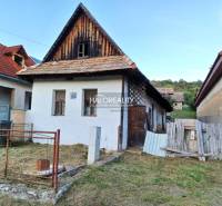 A family house in Ladzany with a sloped roof and a garden, surrounded by other buildings.