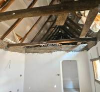 Interior of a family house with exposed wooden roof beams and white plastered walls.