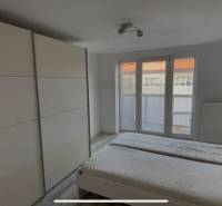 A room in a 2-bedroom apartment with a bed, built-in wardrobe, and French window.