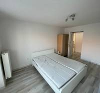 Bedroom in a 2-room apartment with a bed, wardrobe, and white walls.