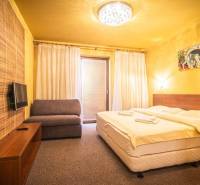 A bedroom in a holiday apartment with a double bed, a sofa, and a television.