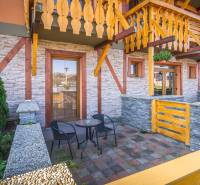 Stone terrace of the Holiday Apartment in Veľká Lomnica with wooden railing and a table.