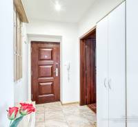 Entrance hall of a 2-room apartment with wooden and white cabinets and tiles.