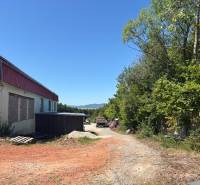 The exterior of the building in Mníchova Lehota with the surrounding nature near warehouses and halls.