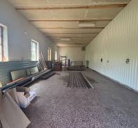 The interior of a hall with storage materials and windows on one side.