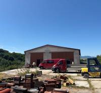 Warehouses and halls in Mníchova Lehota with stacks of bricks, a red van, and a forklift.