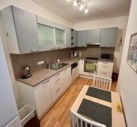 A kitchen in a 2-room apartment with wooden flooring and modern appliances.