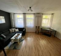 Living room with a black sofa, white table, and a desk in a two-room apartment.