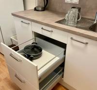 A kitchen with white cabinets, an open drawer, a sink, and an electric kettle in a two-room apartment.