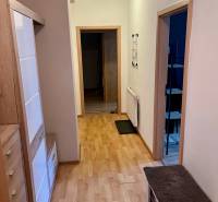 A hallway in a 2-room apartment with light wooden furniture and open doors.