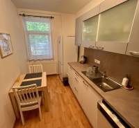 Kitchen in a 2-room apartment with a dining table, white cabinets, and appliances.