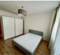 Bedroom in a two-room apartment with a double bed, built-in wardrobe, and wooden floor.