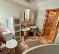 Bathroom of a 2-room apartment with sanitary ware, cabinets, and a large bathtub.