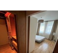 Bedroom in a 2-room apartment with a built-in wardrobe and bed, light curtains.