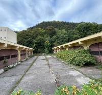 An abandoned complex of buildings near the forest with signs of neglect.