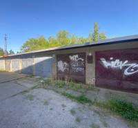 Garages in Zvolen with graffiti on the doors, surrounded by greenery and a concrete area.
