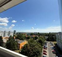 View from a 2-room apartment on Bučinova Street, Bratislava - Vrakuňa, with greenery and cars.