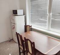 Dining area with a wooden table and chairs in a 2-room apartment.