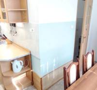 A kitchen connected to a dining table in a 2-room apartment, equipped with basic appliances.