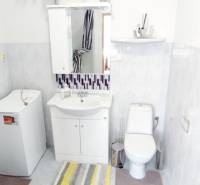 Bathroom in a 2-room apartment with a washing machine, sink, and toilet, tiles in light shades.