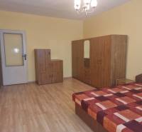 A room in a 2-room apartment with a bed, wardrobe, and dresser on a wooden floor.
