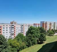 The housing estate with panel buildings on Petzwalova Street in Nitra, surrounded by greenery and a blue sky.
