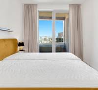 Bedroom in a 2-room apartment with a comfortable bed and a large window with a view.
