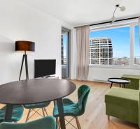 Living room in a two-room apartment with a TV, lamp, table, and a view of the city.