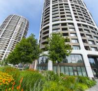 High-rise buildings with modern facades, surrounded by greenery and flowers, on Továrenská Street.