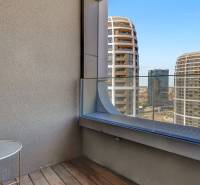 A balcony with a wooden floor and a view of the modern architecture of Bratislava on Čulenova.