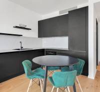 A kitchen in a 2-room apartment with black cabinets and turquoise chairs.