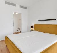 Bedroom in a two-room apartment with a mustard bed and wooden floor.