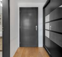 Interior of a 2-room apartment with wooden flooring and a view of the bathroom with a sink.