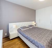 A bedroom with a large bed, wardrobe, and nightstands in a three-room apartment.