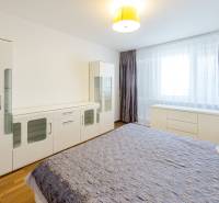 A bright bedroom with a large bed, a dresser, and a wardrobe in a 3-room apartment.