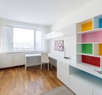 Colorful shelves and white furniture in a 3-room apartment with wooden flooring.