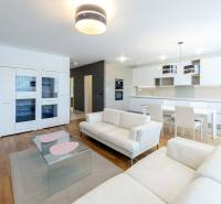 A spacious living room with white sofas, a kitchen, and a dining table in a 3-room apartment.
