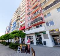 Residential building on Saratovská Street in Bratislava - Dúbravka with shops and a tree-lined avenue.